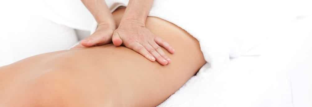 Manos realizando un masaje reductor sobre espalda de mujer