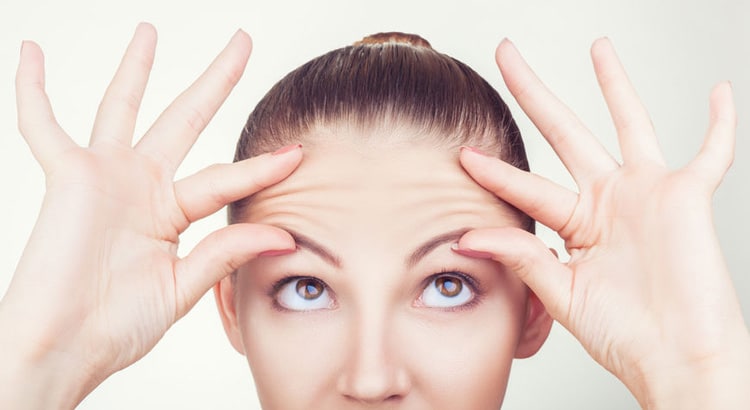 Mujer joven mostrando arrugas de expresión en la frente antes de tratamiento con neuromoduladores